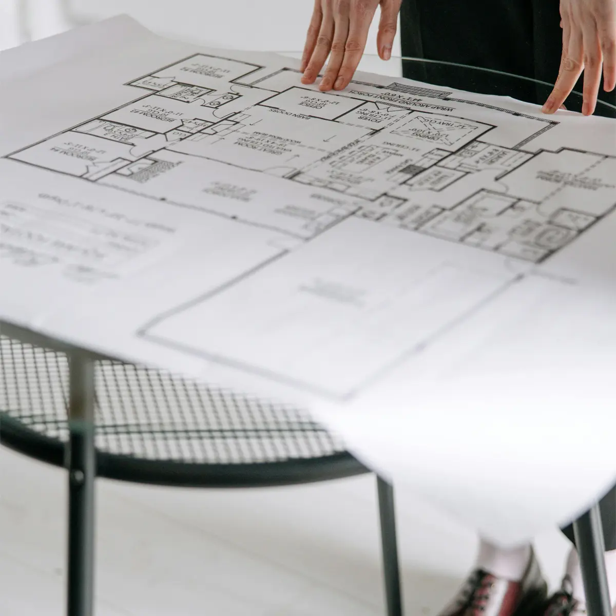 Un architetto controlla un progetto posato su un tavolo di vetro circolare